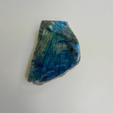 Another angle of the large labradorite slab laying on a neutral background