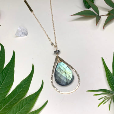 close-up shot of labradorite version the labradorite stone flashes bright blue and yellow well framed by the hammered metal shape surrounding it￼