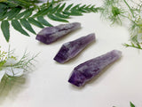 Three amethyst wands on neutral background with a decorative leaves