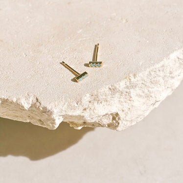 Small gold studs with three tiny turquoise stones set in a line