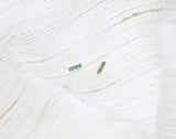 Turquoise studs on white fabric background