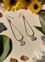 gold hammered metal thin teardrop hoops with single pearl hanging off the bottom of each shape 