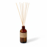 Amber bottle with brown label holding wooden reed sticks￼