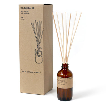amber glass bottle holding reed diffuser sticks next to cardboard box