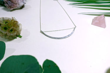 Silver arc necklace showing a long hammered arc sliding along dainty silver chain