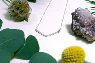 silver necklace made of fine silver chain with gold hammered chevron shape hanging in the middle