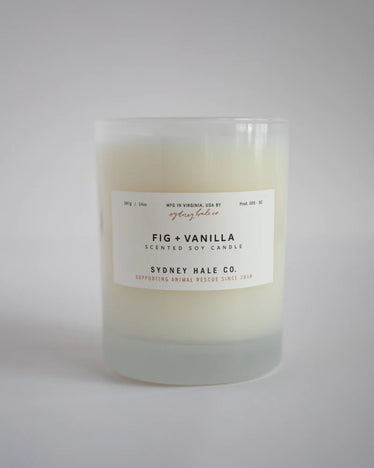 Cream coloured candle in a white frosted glass jar with a white label in a neutral background￼