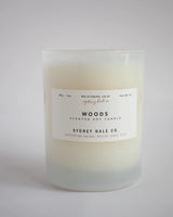 cream colored candle in white frosted glass jar with white label 