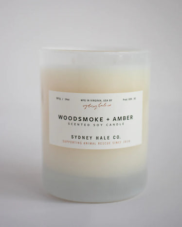 cream colored candle in frosted white glass jar with white label 