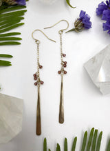 earrings consisting of a short length of chain with small garnet beads gradually hanging off with a metal hammered paddle dangling at the end