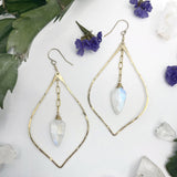 hammered petal moonstone drop earrings on white background earrings consist of a hammered pointed teardrop shape resembling a petal with a spade shaped moonstone hanging in the middle off of a small length of chain￼