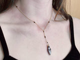 Woman wearing diamond drop necklace in dendrite agate. the necklace hangs above collarbones with black onyx beads cut into the chain￼