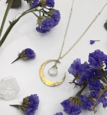 Hand hammered gold crescent moon shape with round moonstone suspended in the middle hanging off of the necklace