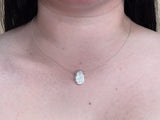 Slightly flat single pearl on dainty silver chain worn by a woman