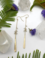 earrings consisting of a short length of chain with small moonstone beads gradually hanging off with a metal hammered paddle dangling at the end￼