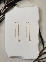 threader earrings featuring a tiny gold delicate chain and a peachy cream round pearl hanging off the end￼