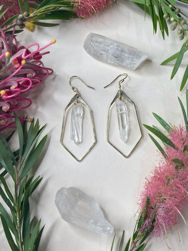 Courts hammered polygon earrings on white background earrings are a hammered metal pointed at the bottom shape with a raw quartz in the middle