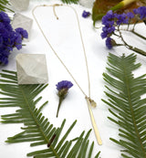 Hammered stick stone drop necklace on white background with flowers and crystals