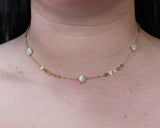 Woman wearing stone in sequin necklace with sections of gold sequin chain and small round freshwater pearls