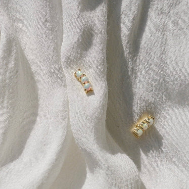 Golden Opal studs on linen background the studs feature three opal stones in a curved line
