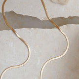 Gold herringbone Kay necklace against two slate stones